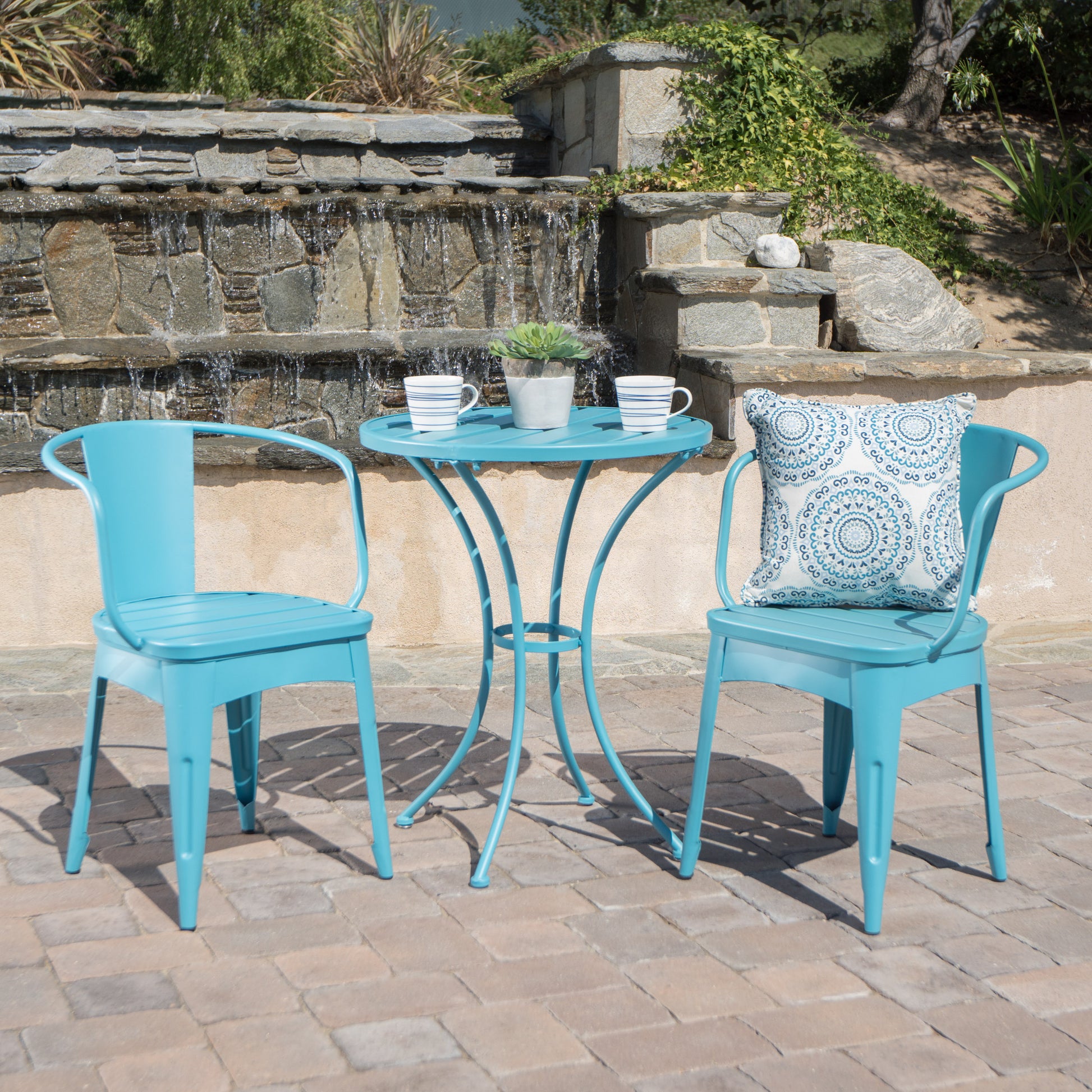 A blue 3-piece patio bistro set, consisting of two chairs and a round table, is placed on a patio with a pool and greenery in the background, KOSSMAI